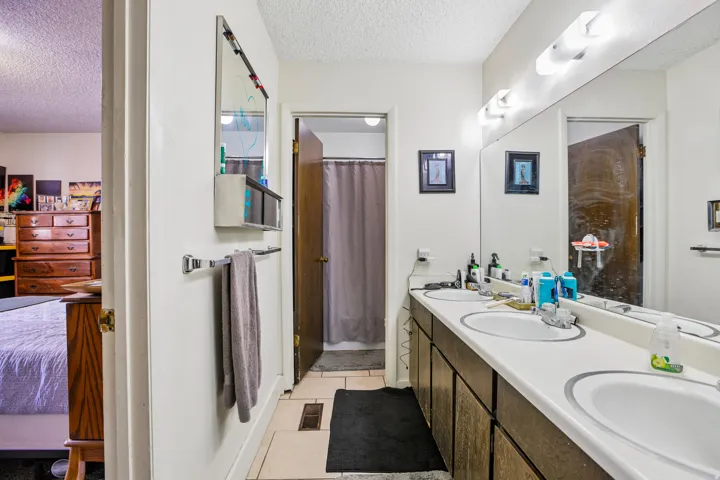 Dual vanity with white countertops, integrated sinks, and overhead lighting