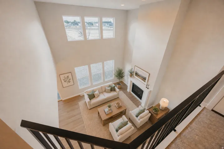 Two-story living area with high ceilings, featuring a built-in fireplace with mantel, wood-finish flooring, and multiple large windows
