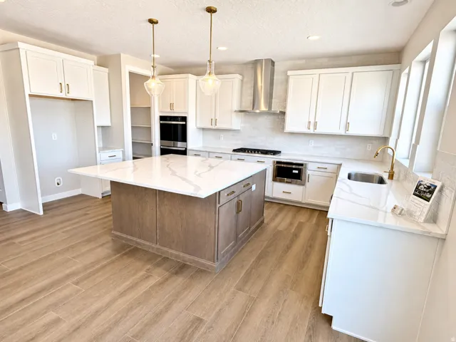 Kitchen featuring a center island with a stone-finish countertop, white cabinetry, wood-finish flooring, and a stainless steel oven and range hood