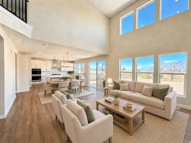 Two-story living area with high ceilings, wood-finish flooring, and multiple windows