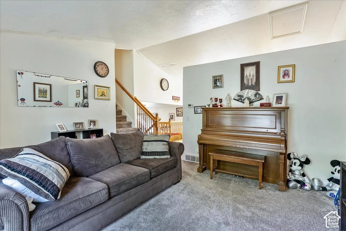 Carpeted flooring extending throughout, white wall finishes, and a staircase with wood-finish railings