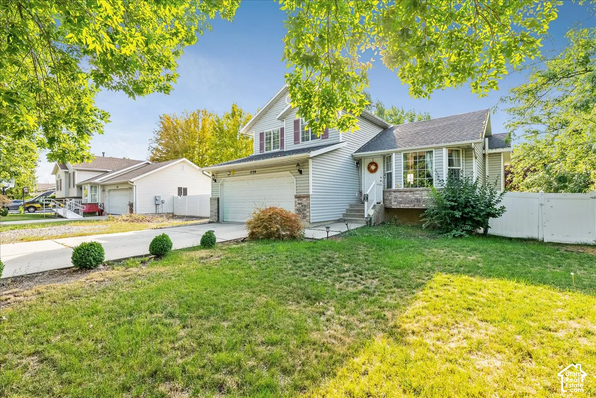 Two-story residence featuring siding exterior, an attached garage, a concrete driveway, and a front yard with mature landscaping