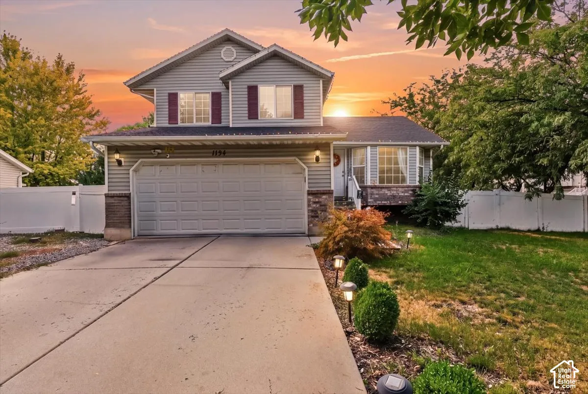 Two-story residence with gray siding, attached garage, and stone accents