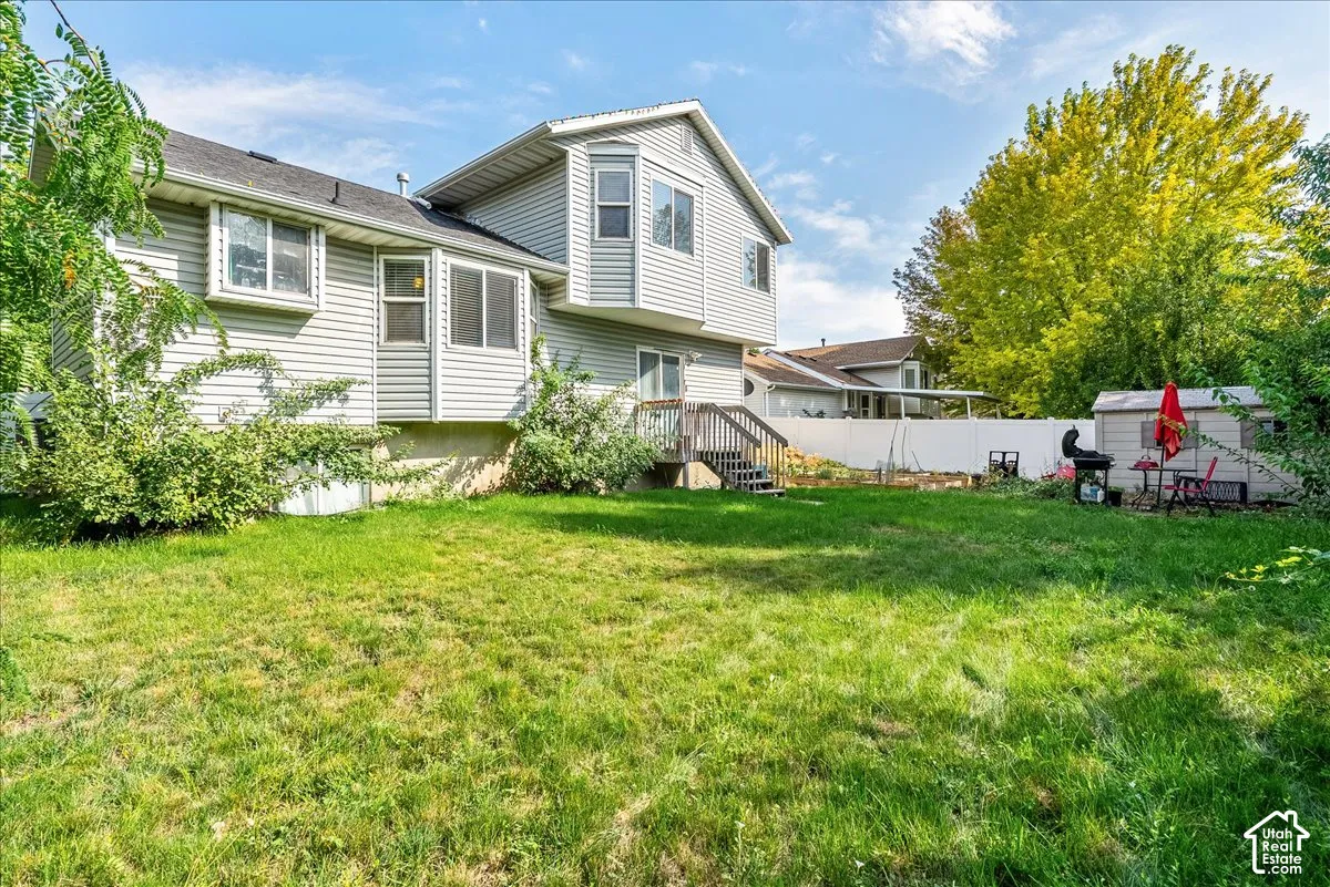 Spacious backyard with a wood-finish deck, white vinyl fencing, and a storage shed