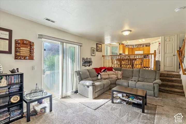 Sliding glass door, light-toned wall paint, neutral-toned carpet, wood railing, recessed ceiling light
