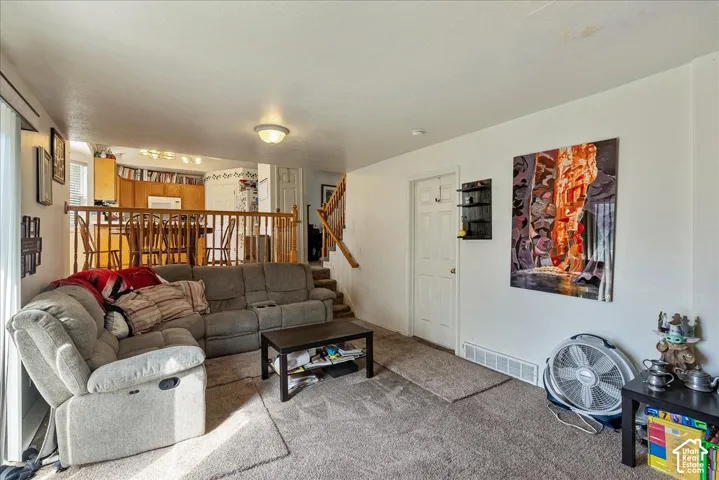 Carpeted living area with a white painted wall, a white door, and a built-in shelf