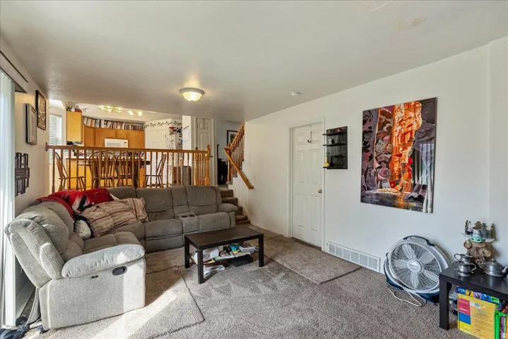 Carpeted living area with a white painted wall, a white door, and a built-in shelf