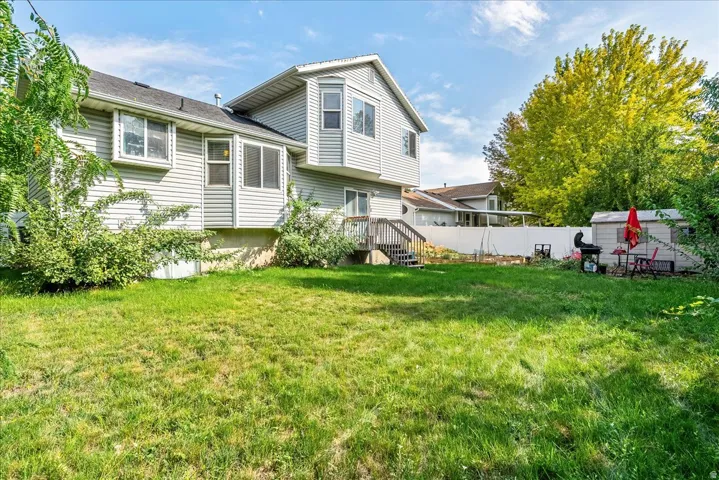 Spacious backyard with a wood-finish deck, white vinyl fencing, and a storage shed