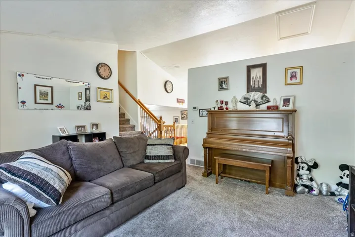 Carpeted flooring extending throughout, white wall finishes, and a staircase with wood-finish railings