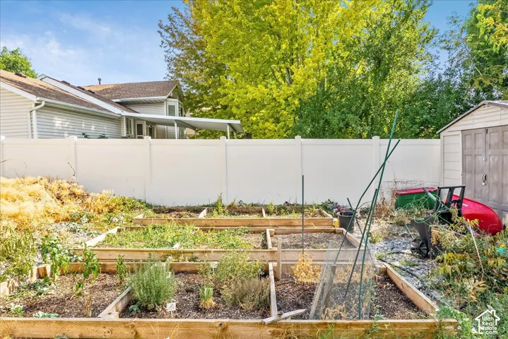 Backyard featuring multiple raised garden beds, a utility shed, and a privacy fence