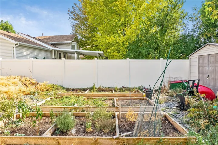 Backyard featuring multiple raised garden beds, a utility shed, and a privacy fence
