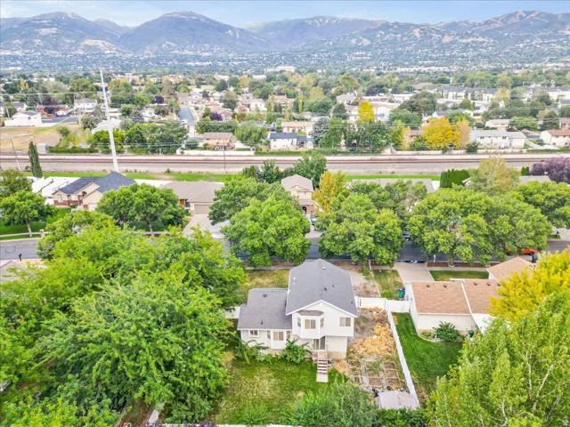 Mountain backdrop, residential neighborhood setting, mature trees, railroad tracks, and visible property structures