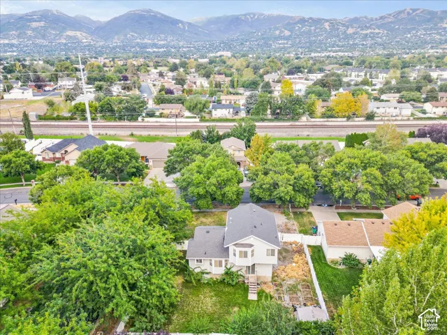 Mountain backdrop, residential neighborhood setting, mature trees, railroad tracks, and visible property structures