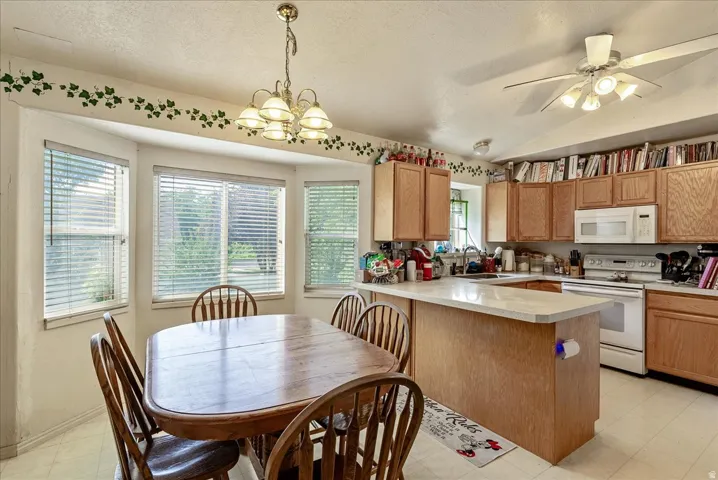 Kitchen featuring wood-finish cabinetry, white appliances, and a central island with a light-toned countertop