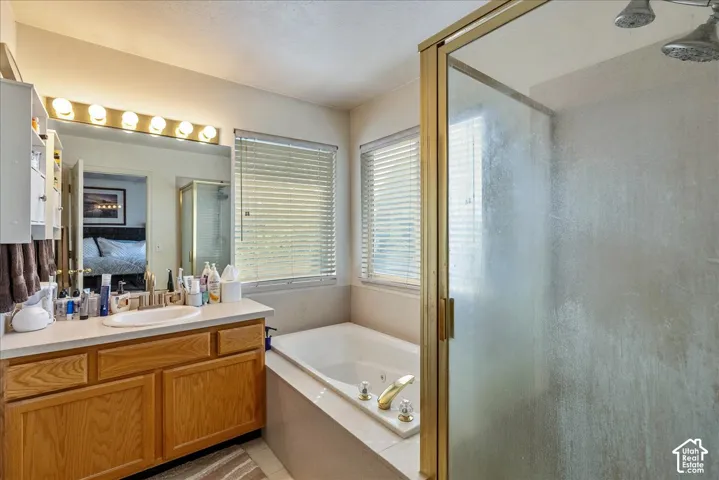 Dual vanity with wood-finish cabinetry, built-in soaking tub, and a shower with a gold-tone framed glass enclosure