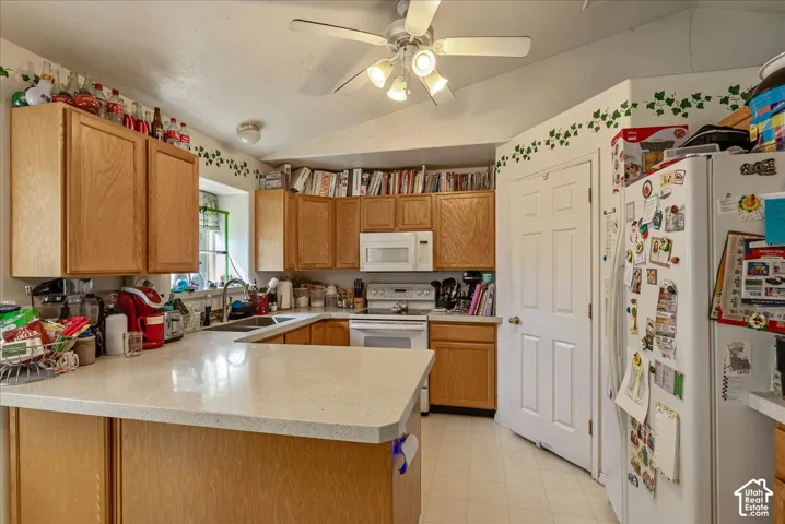 U-shaped kitchen featuring wood-finish cabinetry, light-toned countertops, and white appliances