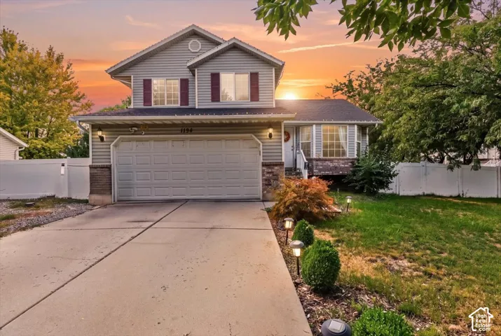 Two-story residence with gray siding, attached garage, and stone accents