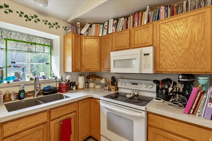Recessed lighting, wood-finish cabinetry, built-in microwave, dual basin sink, and a multi-burner electric range