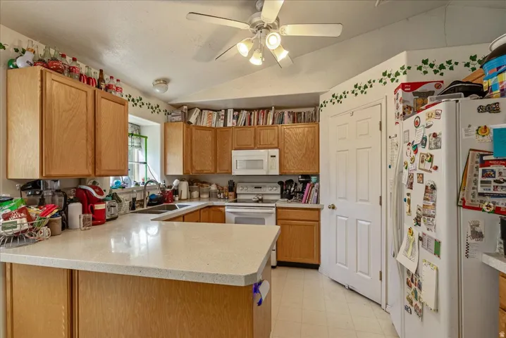 U-shaped kitchen featuring wood-finish cabinetry, light-toned countertops, and white appliances