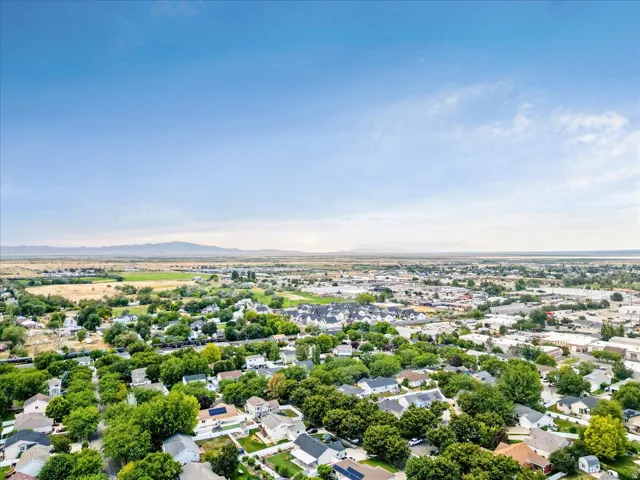 Expansive residential area with mature tree coverage, clear skies, and distant mountain ranges