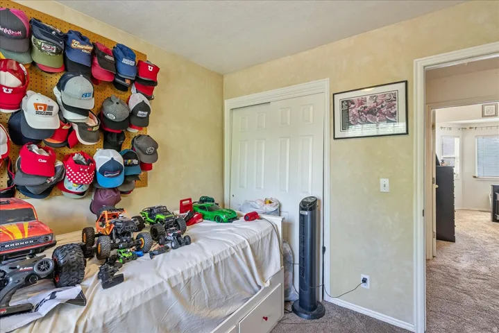 Room featuring textured wall finish, carpet flooring, a white sliding closet door, and a white interior door