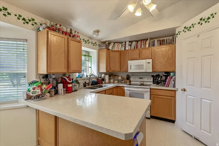 Kitchen featuring wood cabinetry, light-toned countertops, a white electric range, and a white microwave
