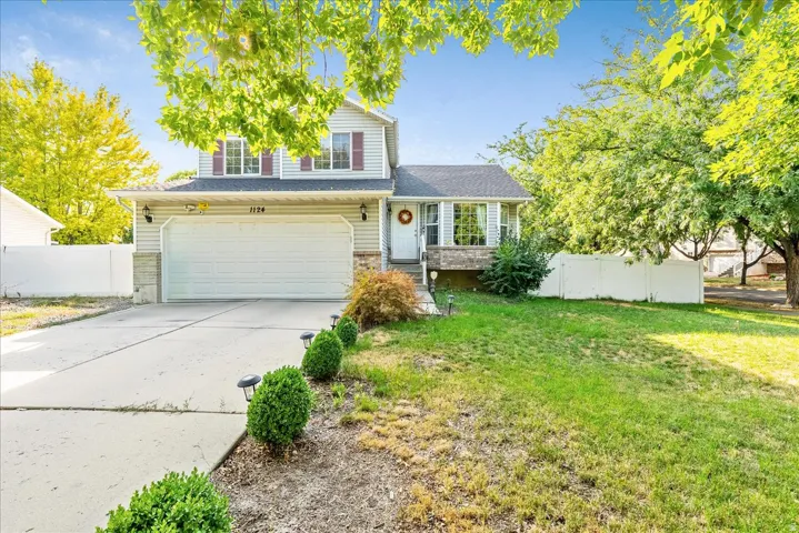 Two-story residence featuring light siding, a two-car garage with a concrete driveway, and a front lawn with established landscaping
