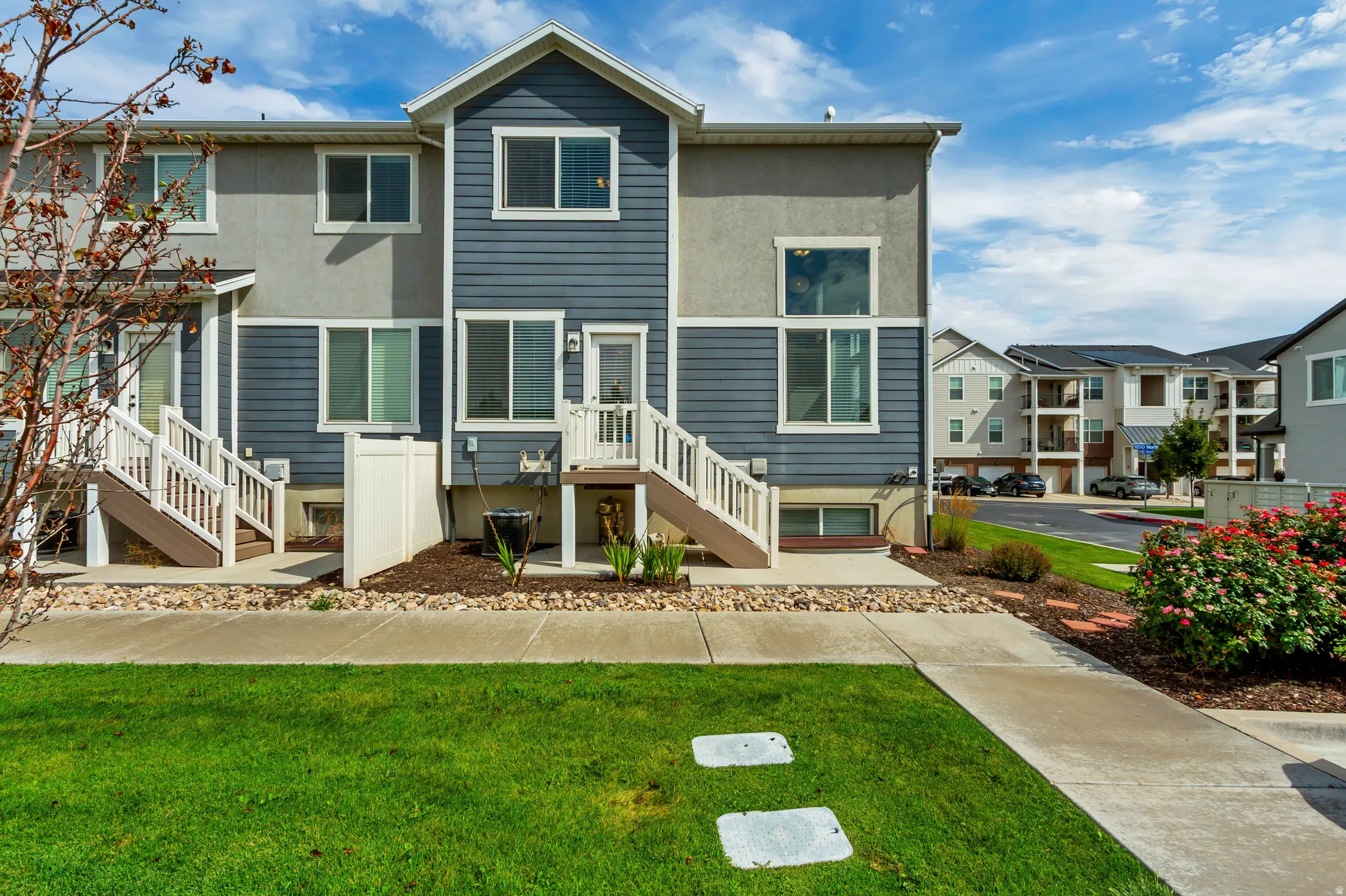 Multi-level townhouse exterior featuring blue siding and light grey stucco.