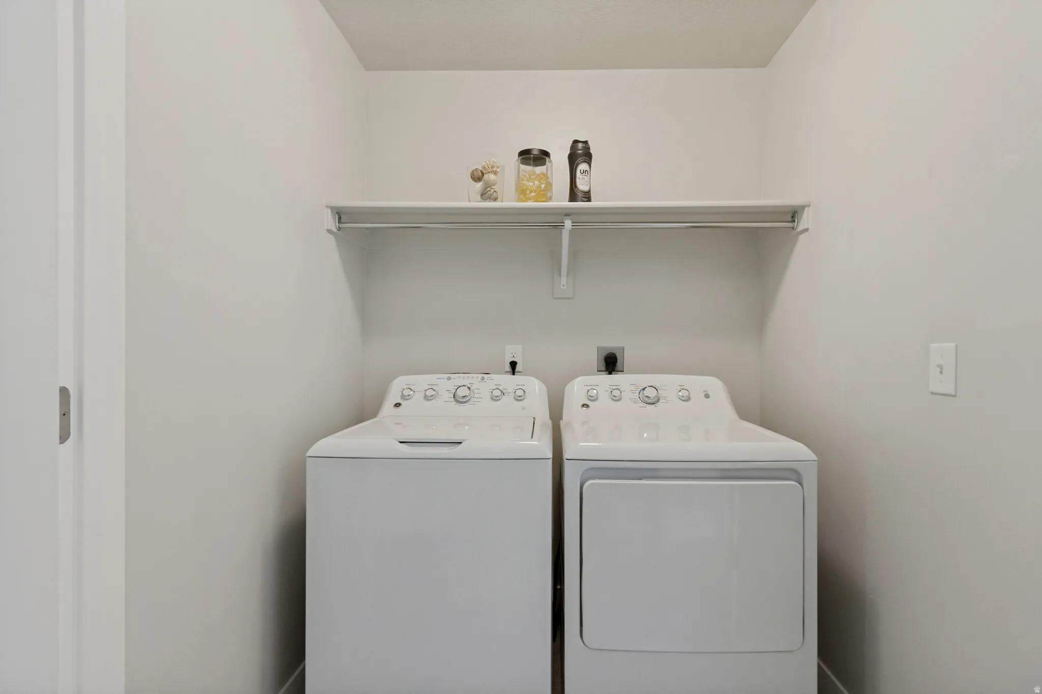 Laundry area with a white storage shelf, and hanging rod.