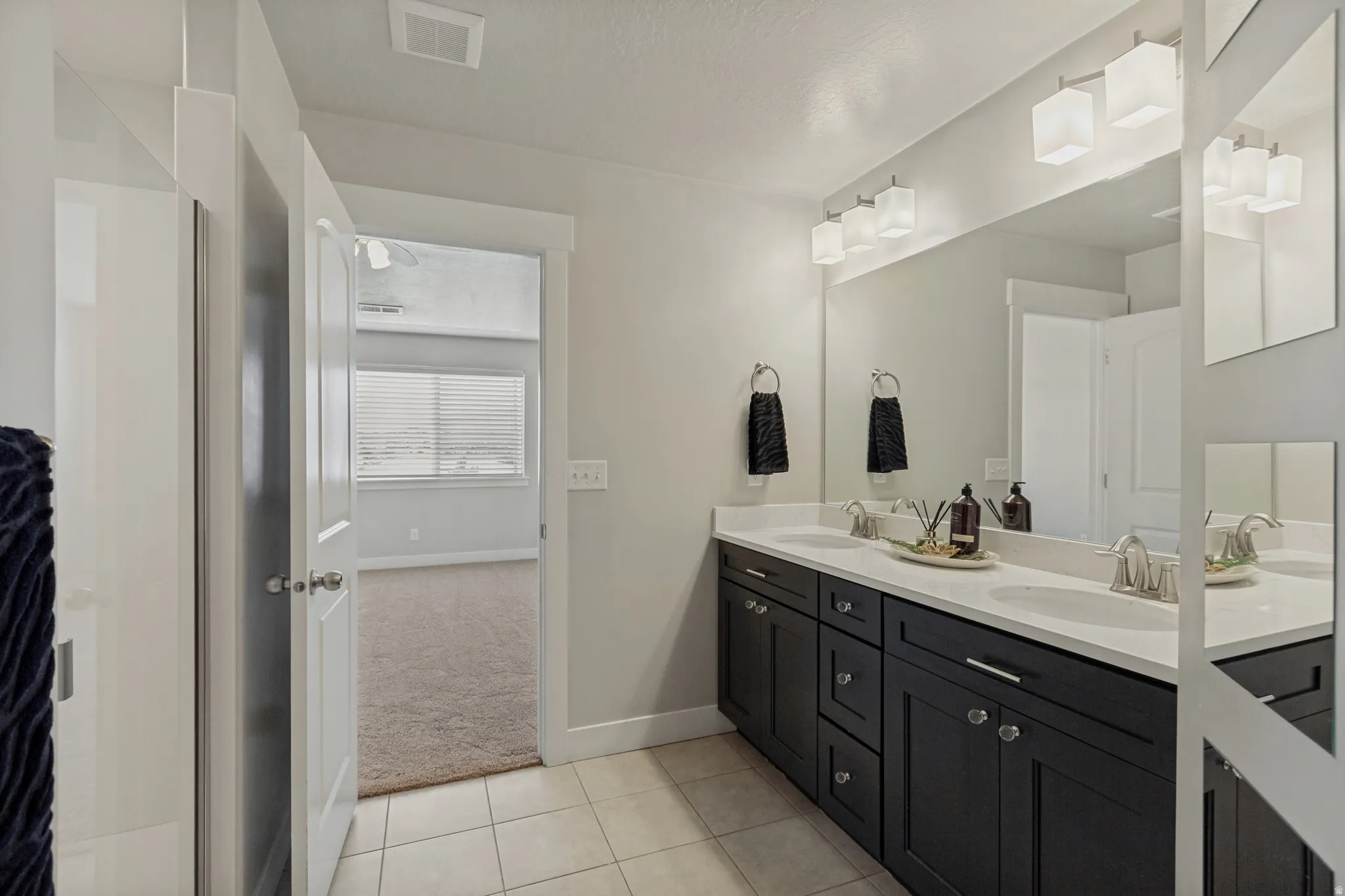 Owners bathroom with dual vanity with white countertops, dark wood-finish cabinetry, and brushed nickel fixtures.