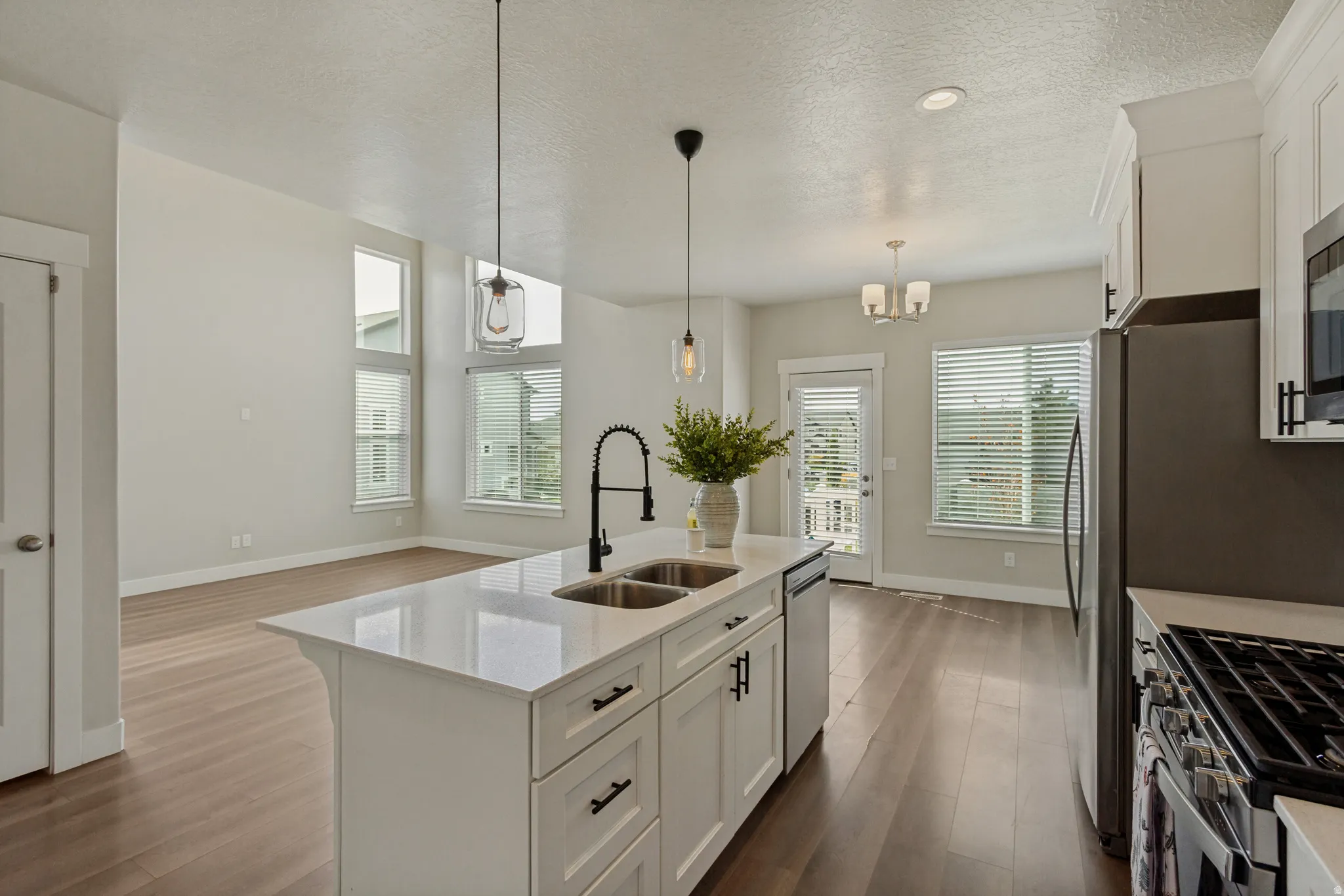 Kitchen island with a double basin sink, quartz countertop, and black modern fixtures.