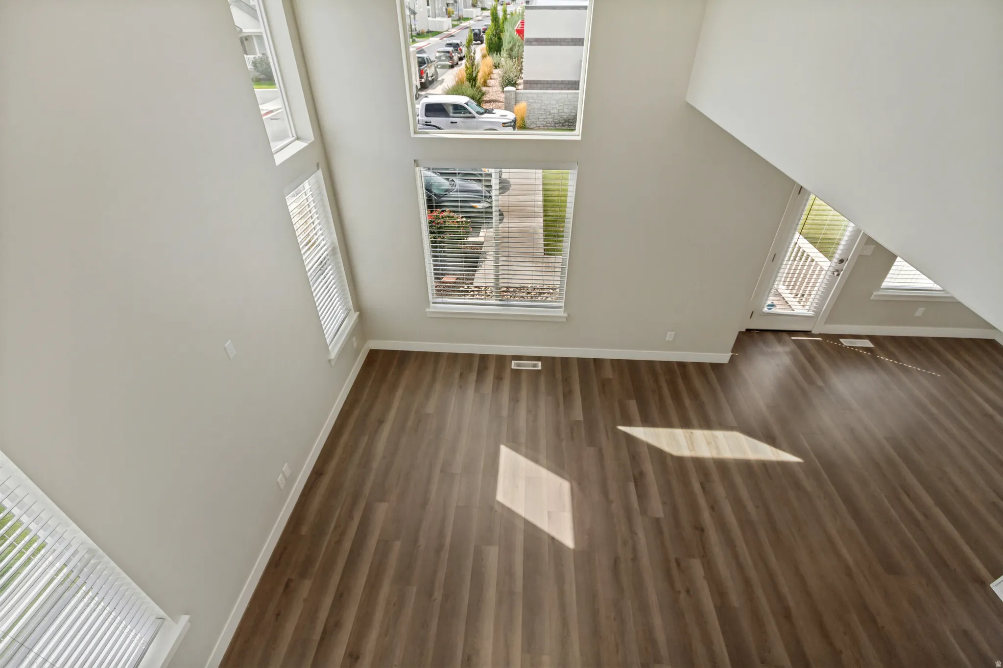 Beautiful high ceilings, multiple windows, wood-finish flooring, white trim, light gray wall paint.
