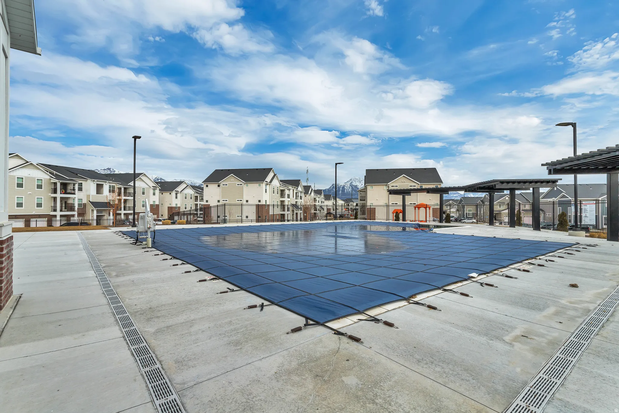 Community pool with concrete decking, surrounding residential buildings, and mountain scenery.