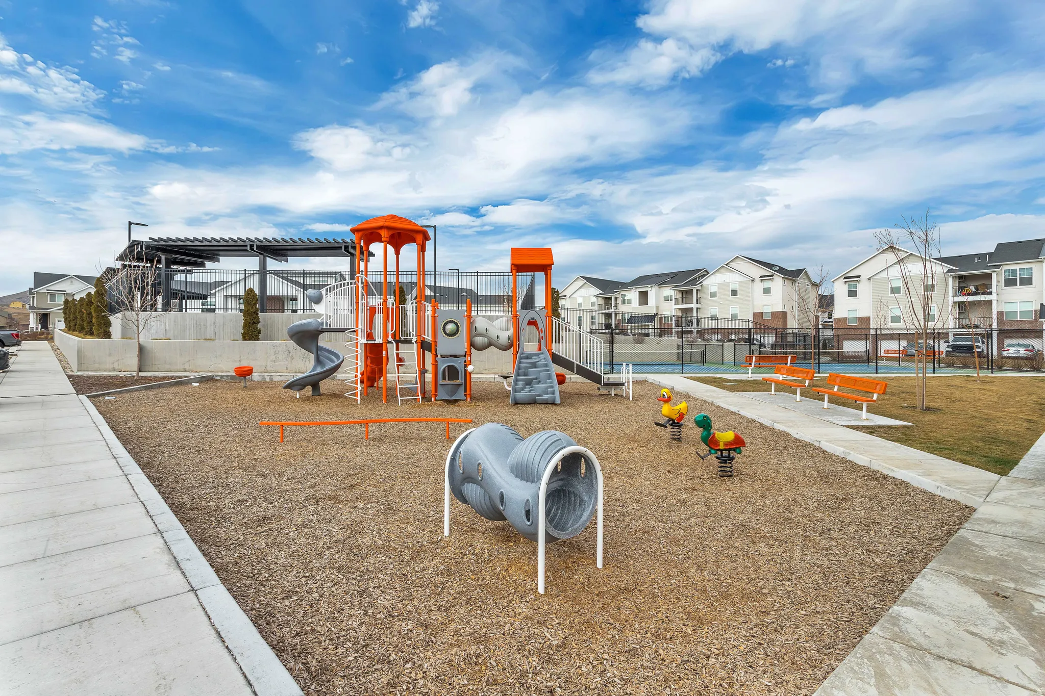 Community playground featuring slides, climbing structures, tunnel, and spring riders.