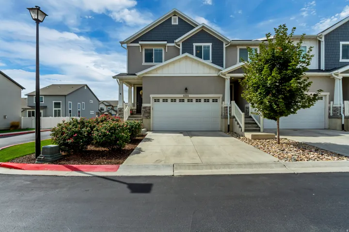 Two-story townhome with attached garage, covered porch, concrete driveway, and landscaped front yard.