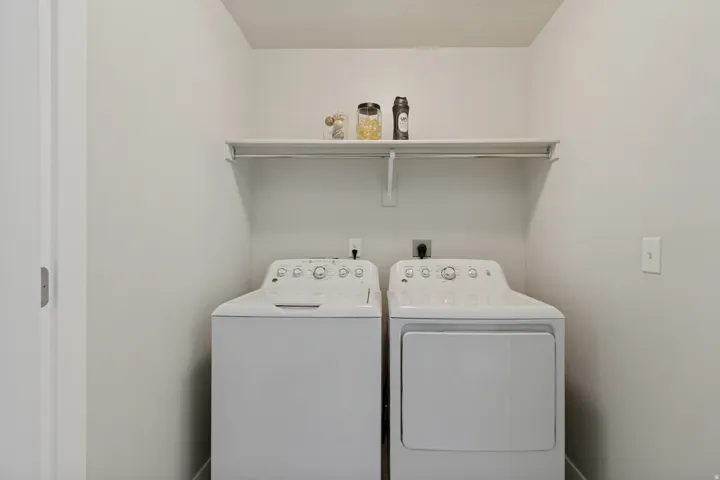Laundry area with a white storage shelf, and hanging rod.