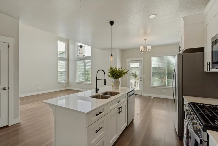 Kitchen island with a double basin sink, quartz countertop, and black modern fixtures.