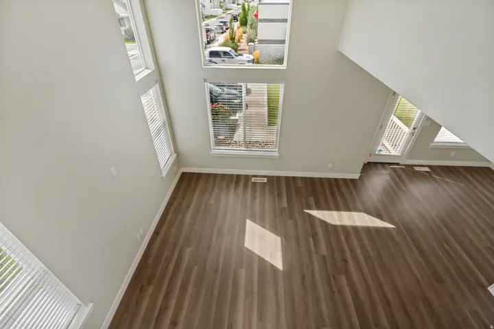 Beautiful high ceilings, multiple windows, wood-finish flooring, white trim, light gray wall paint.