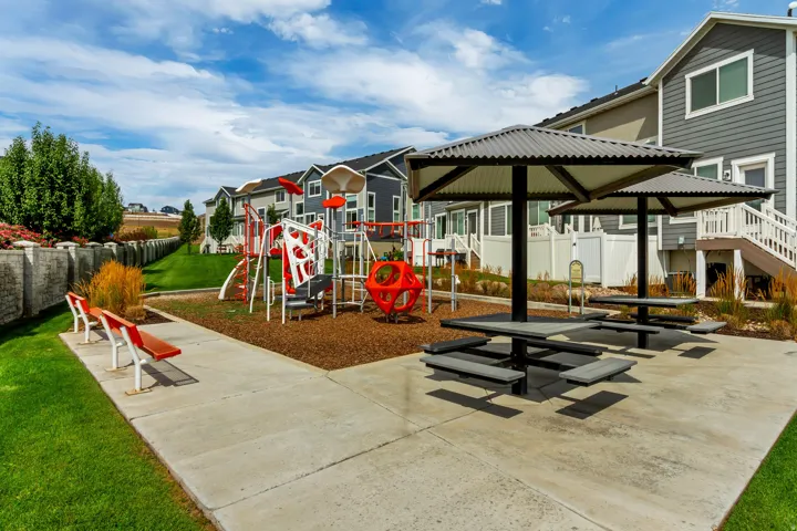 Community play area with playground equipment, benches, and shaded picnic tables.