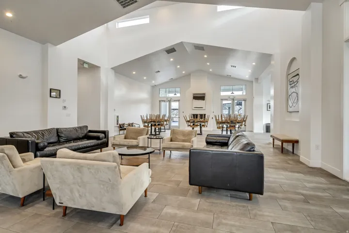Clubhouse living room common area featuring vaulted ceilings, recessed lighting, and wood-finish flooring.