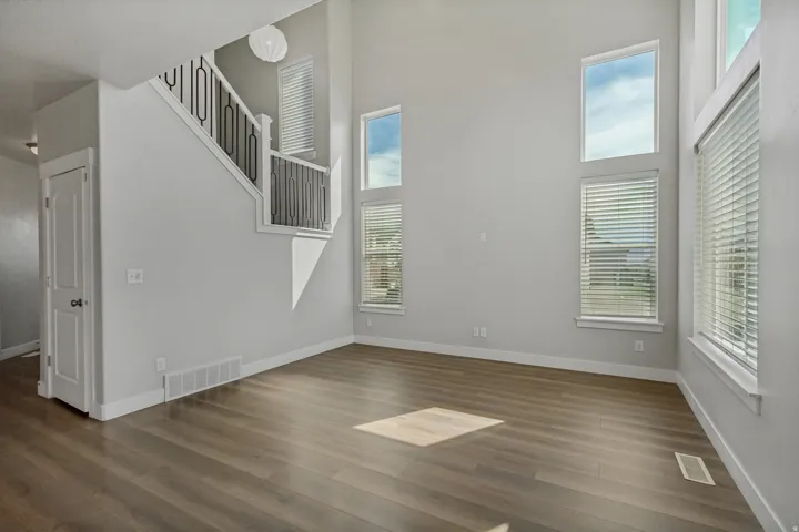 Soaring ceilings with transom windows, wood-finish flooring, and a modern staircase with wrought iron balusters.