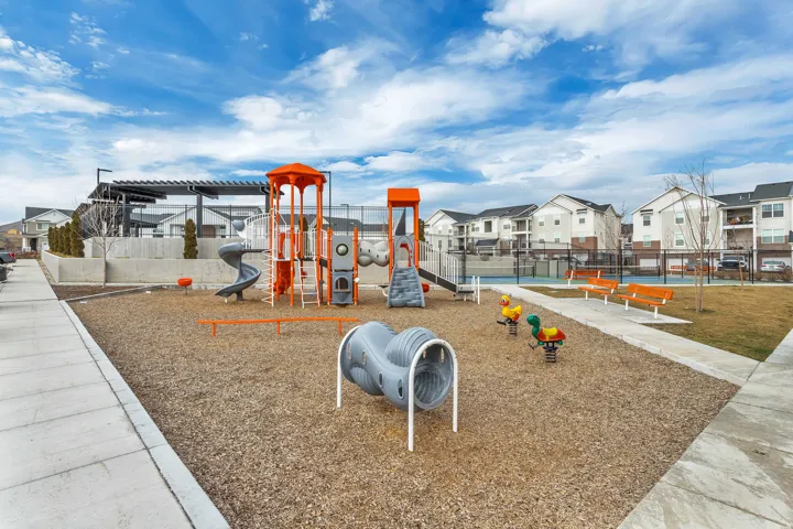 Community playground featuring slides, climbing structures, tunnel, and spring riders.