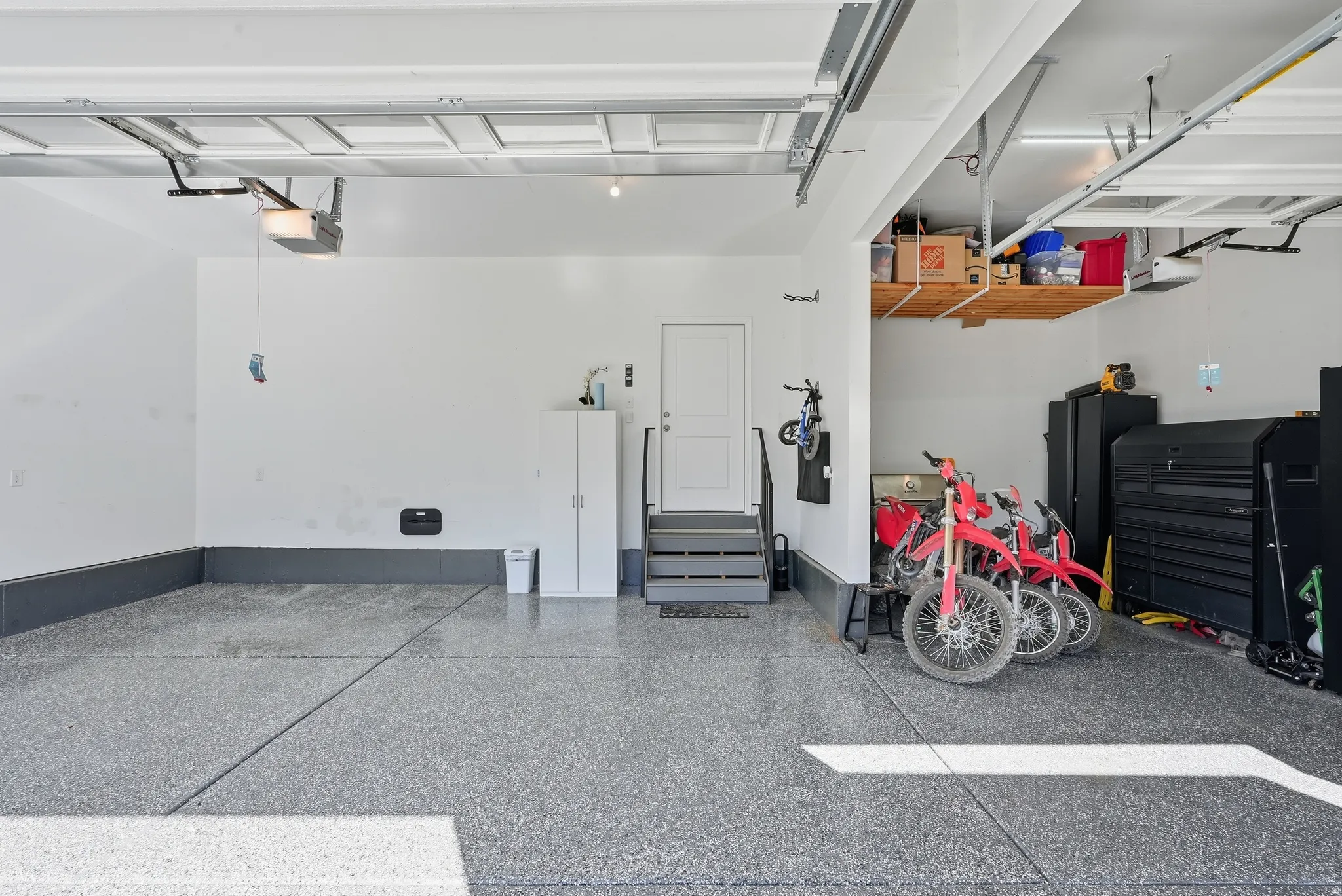 Spacious garage featuring a durable epoxy floor, integrated overhead storage, and an interior access door