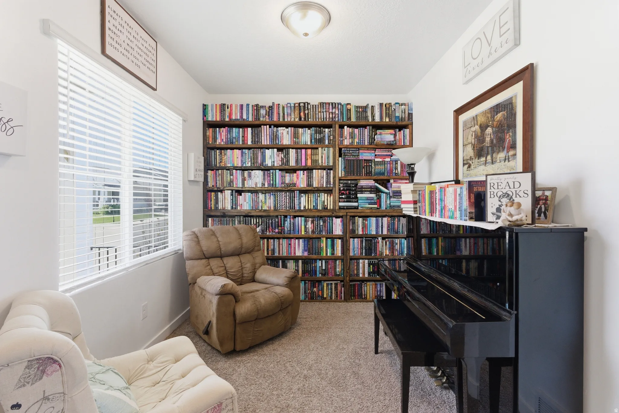 Built-in floor-to-ceiling bookshelves, wall-to-wall carpeting, and a window with blinds