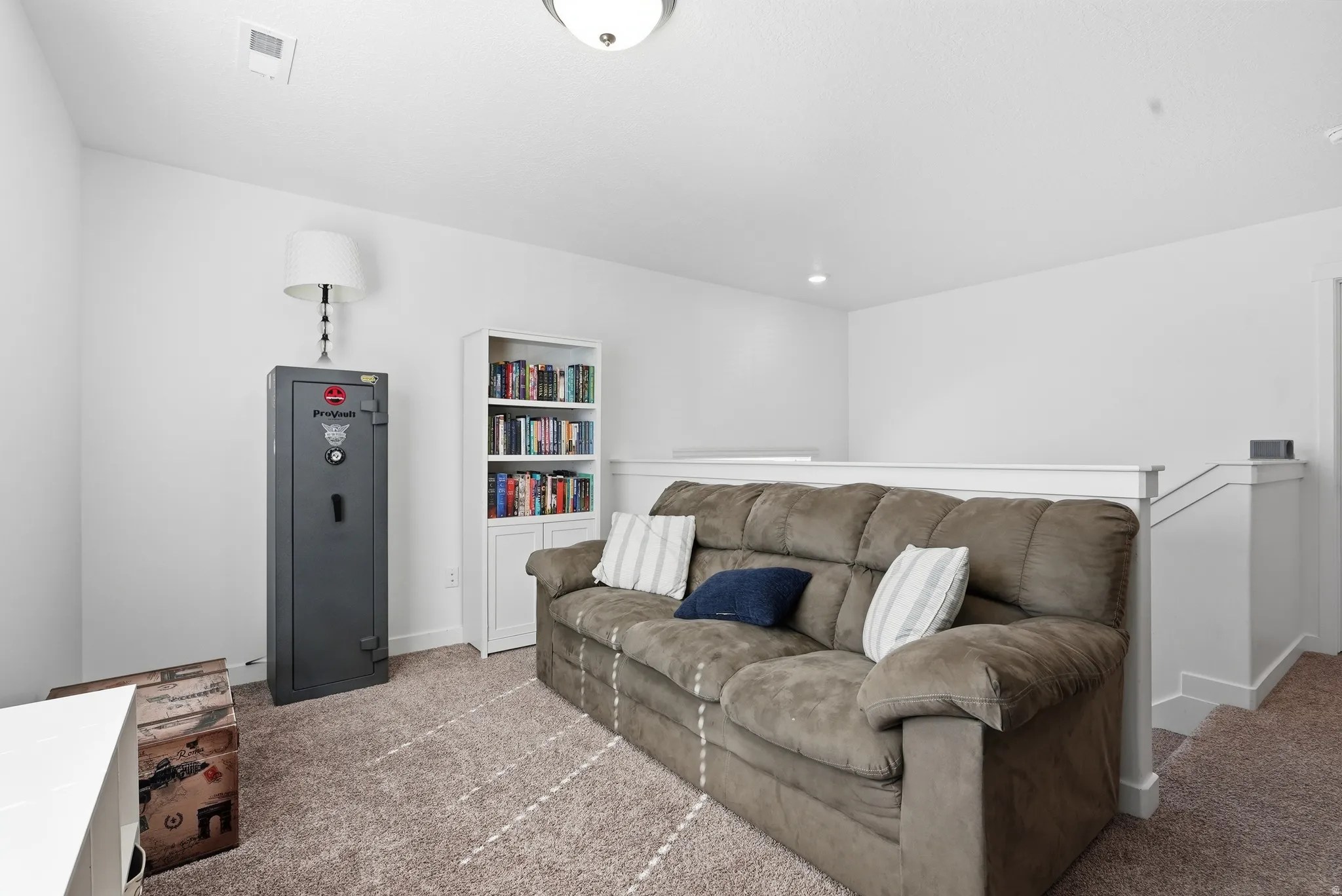 Carpeted landing area featuring a built-in bookshelf and a white painted railing