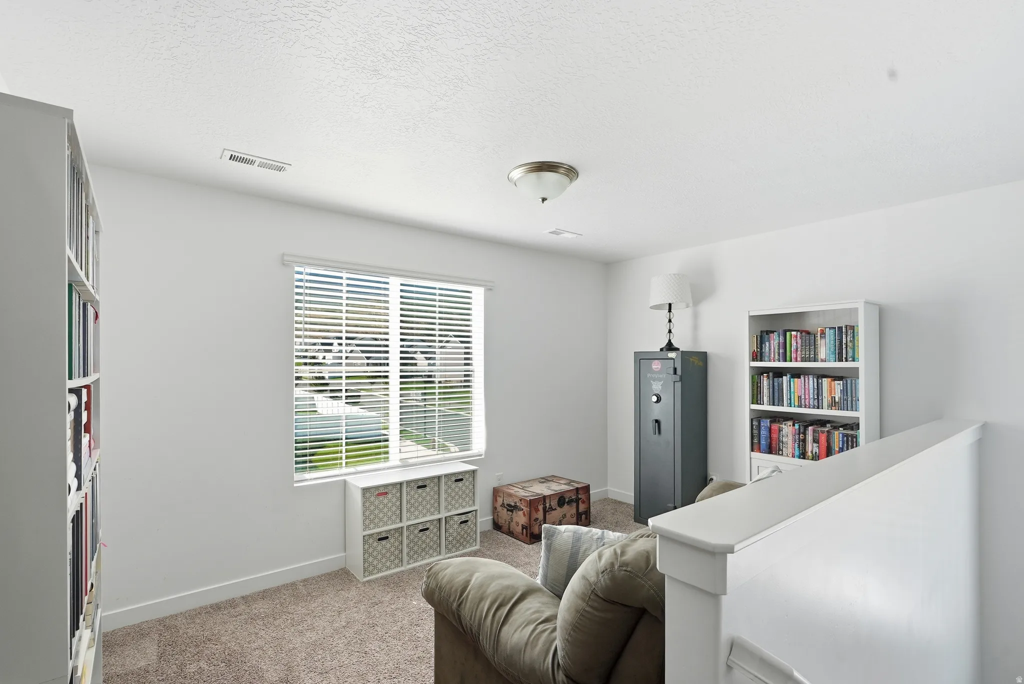 Carpeted flooring with white wall finishes, a window with blinds, and white built-in shelving
