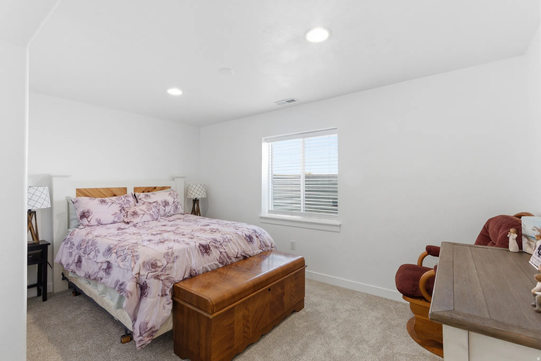 Plush carpeting, a single window with blinds, and recessed ceiling lighting