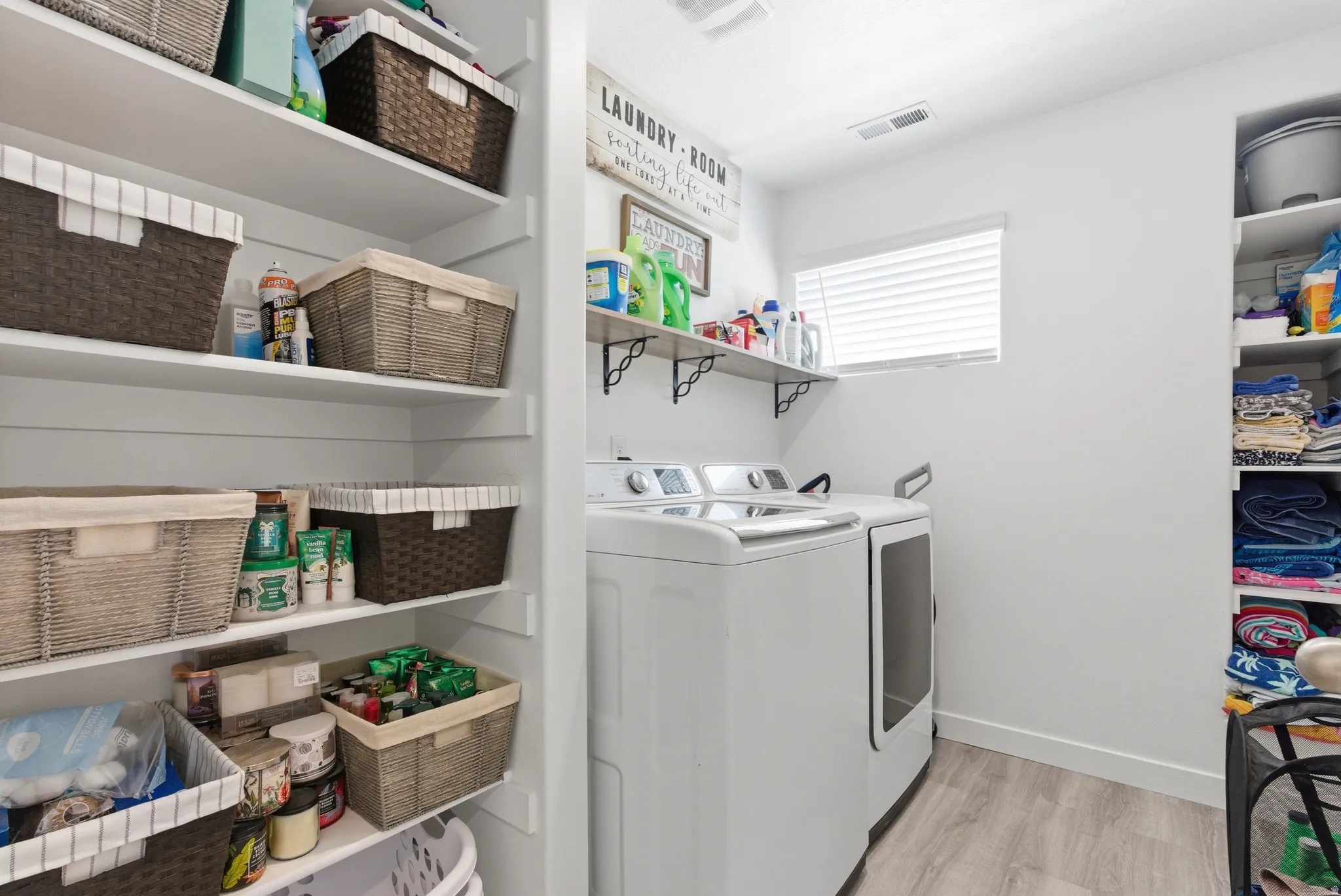 Laundry area with wood-finish flooring, built-in shelving, and a window with blinds