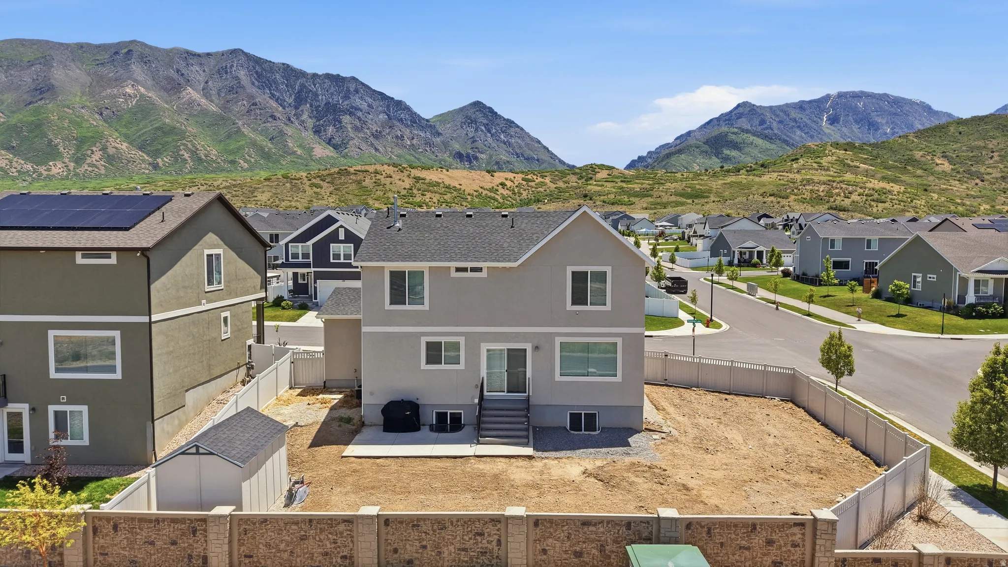 Rear exterior featuring a concrete patio, shed, and mountain backdrop