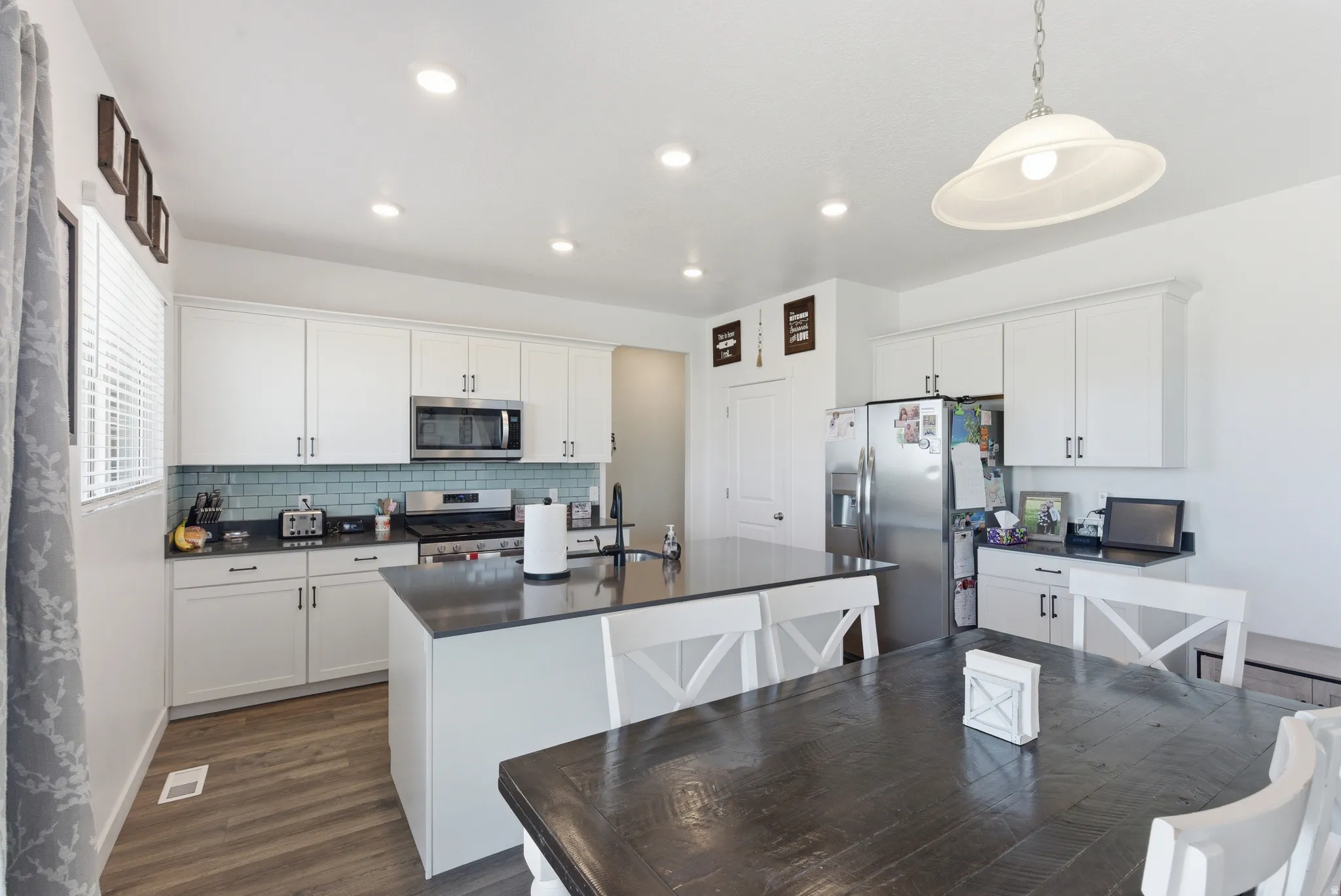 Kitchen featuring an island, white cabinetry, stainless steel appliances, and wood-finish flooring